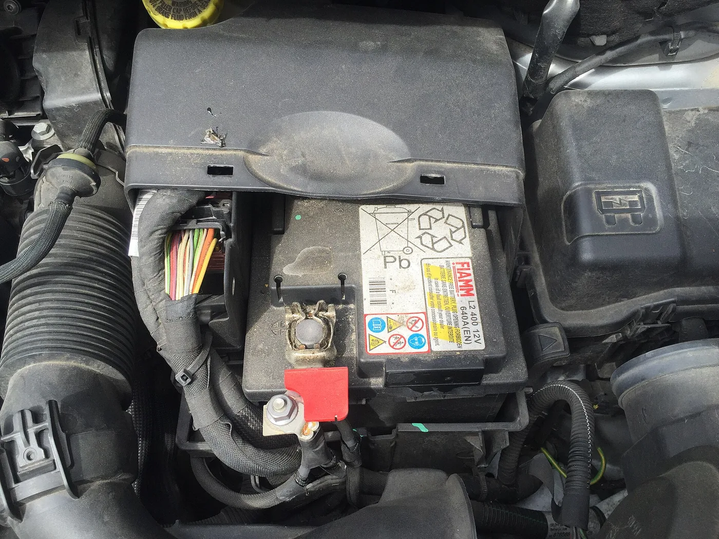 Batterie de démarrage 12 V en place dans un compartiment moteur, cosses visibles