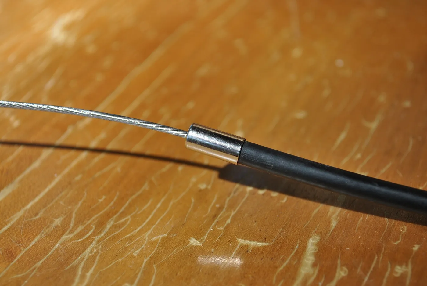 Câble de commande sortant de sa gaine, avec l'embout métallique de gaine en butée
