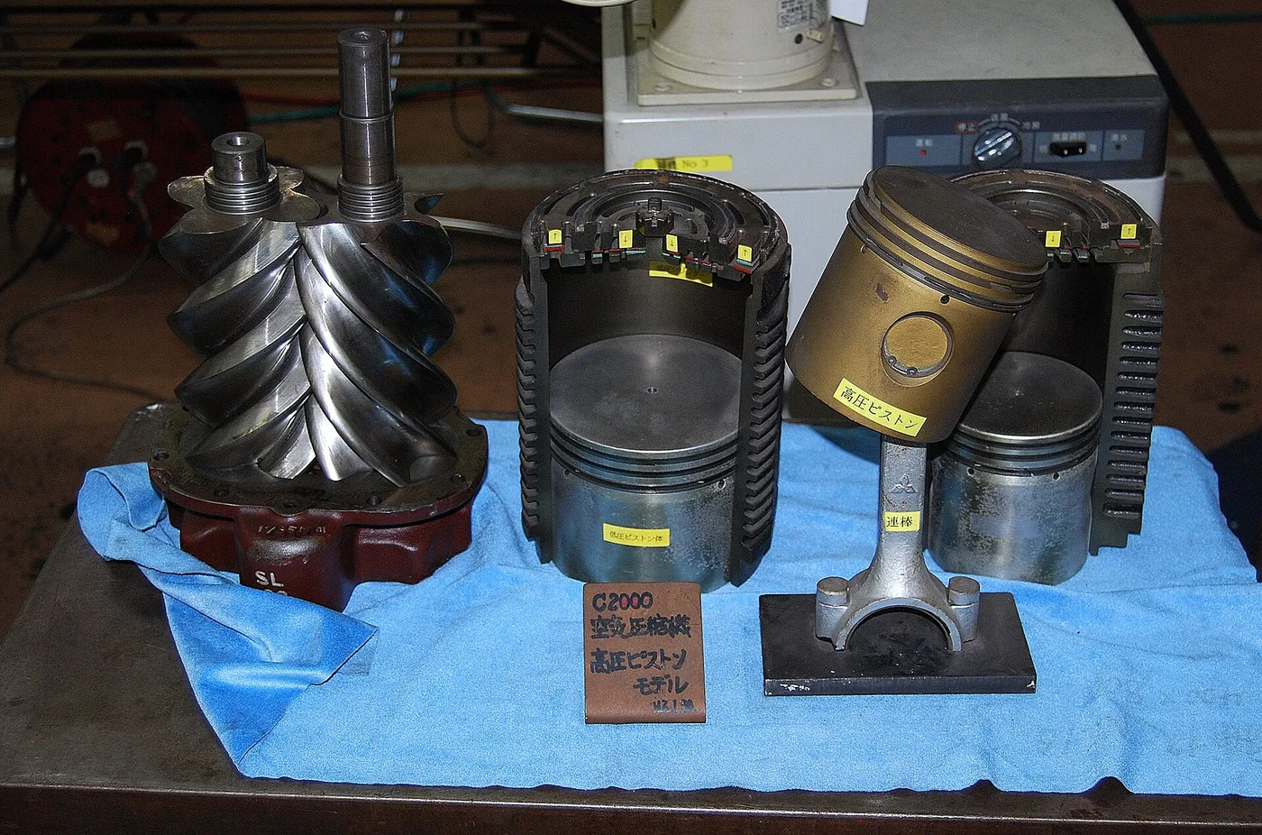 Vis de compresseur et pistons de compresseur exposés côte à côte en atelier
