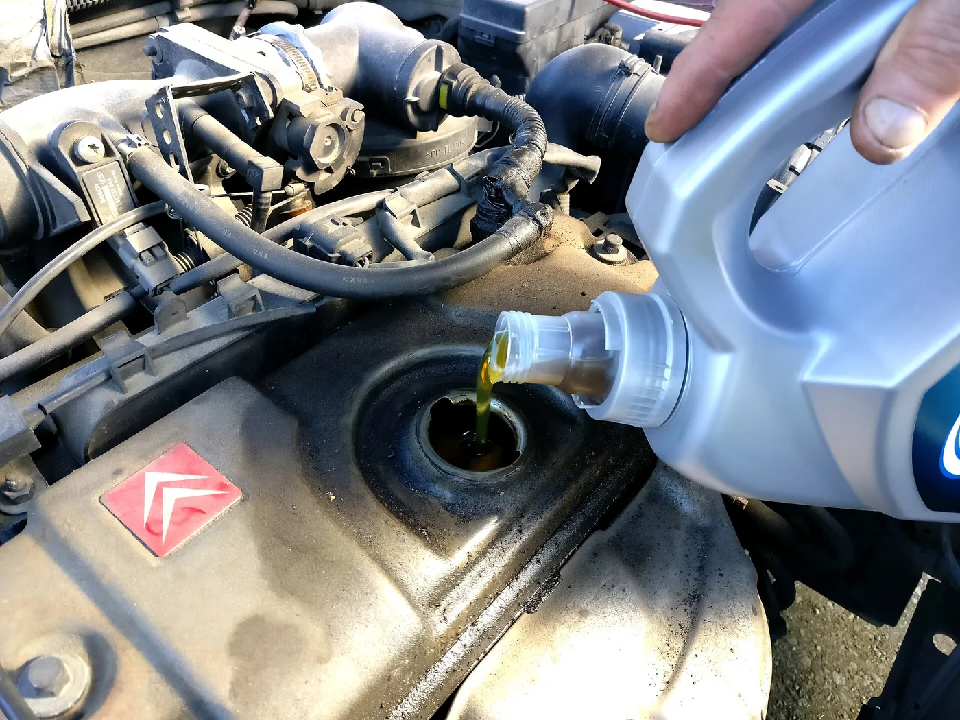 Versement d'huile moteur neuve dans le bouchon de remplissage d'un moteur
