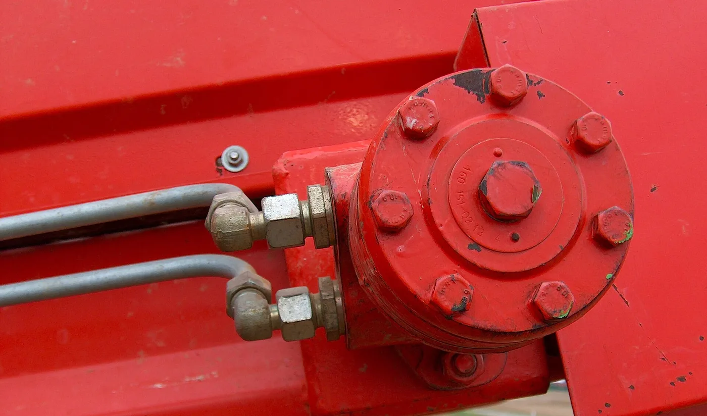 Moteur hydraulique monté sur le bâti d'une machine, alimenté par deux tubes rigides