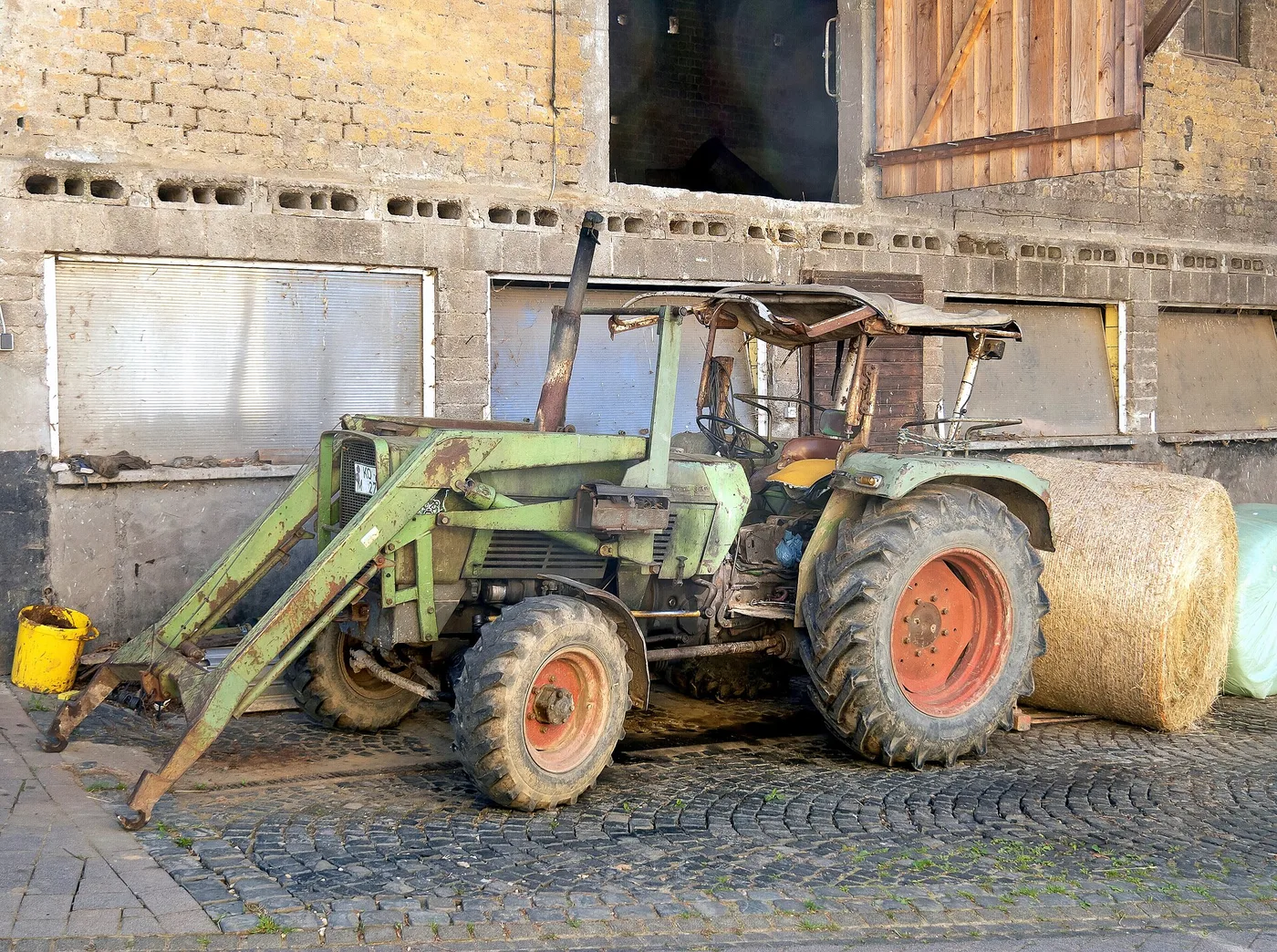 Tracteur ancien équipé d'un chargeur frontal, bras, vérins et outil au sol