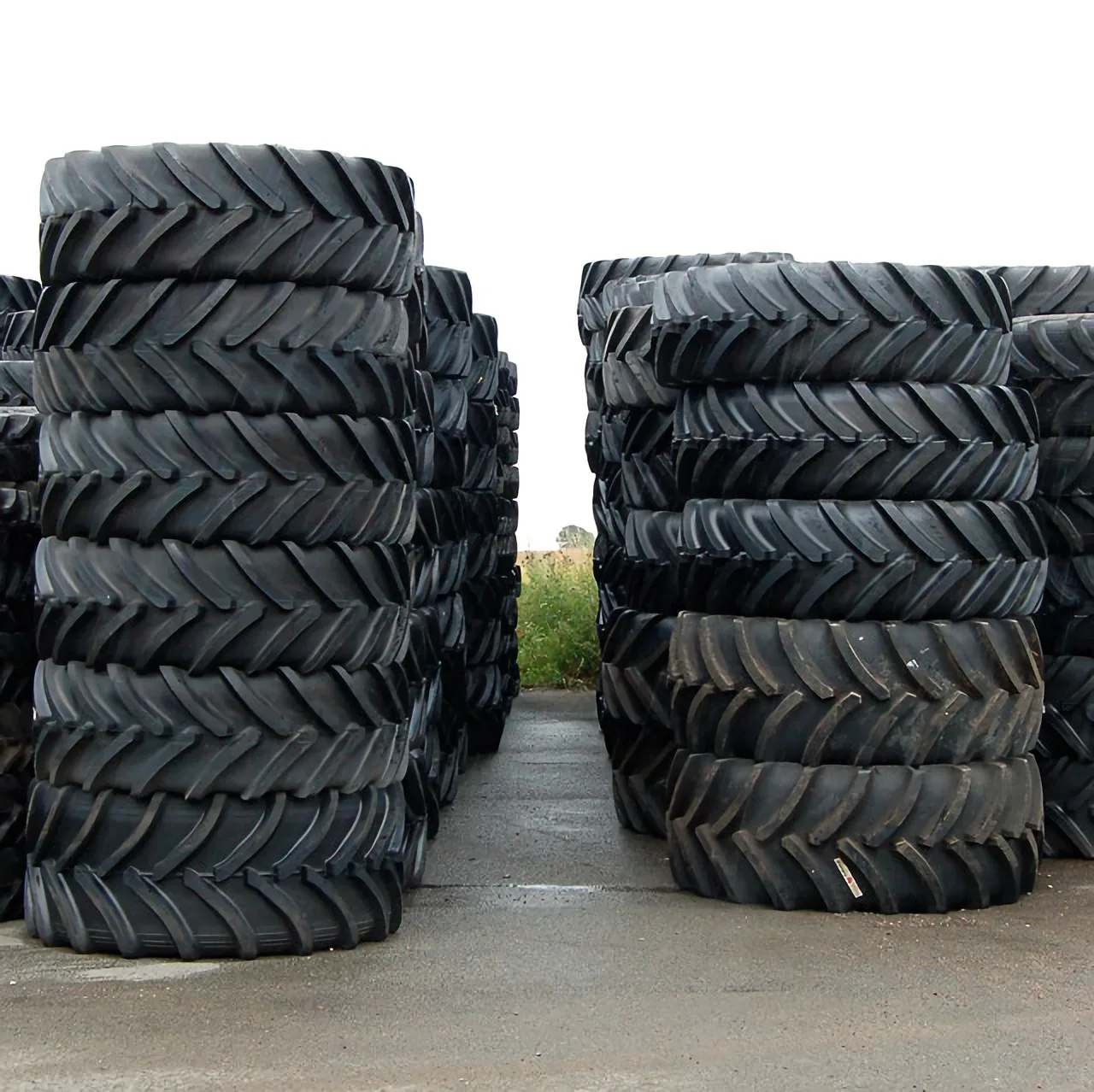 Piles de pneus de tracteur agricole neufs à barrettes stockés dans une cour