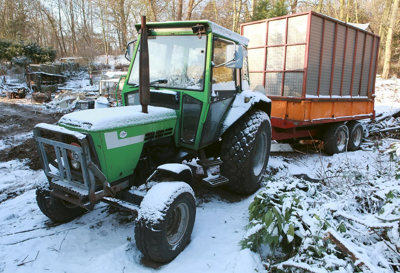 Tracteur agricole et sa remorque couverts de neige en hiver